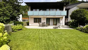 Ansicht des Hauses von hinten mit gepflegtem Garten, Terrasse und Balkon im Obergeschoss.