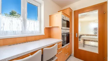 Integrierte Küchenzeile mit Backofen, Mikrowelle und Arbeitsbereich am Fenster mit Sitzgelegenheiten.