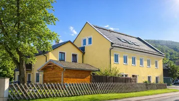 Gut gepflegtes Wohnhaus mit gelber Fassade, Satteldach und Dachfenstern in ländlicher Umgebung.