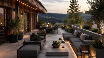 Großzügige Terrasse mit modernen Lounge-Möbeln, Essbereich und malerischem Bergblick bei Sonnenuntergang.