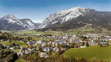 Weitläufige Luftaufnahme einer alpinen Stadt umgeben von majestätischen Bergen.