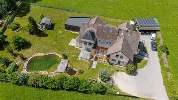 Luftaufnahme des Anwesens mit großem Garten, Teich und Photovoltaikanlage in ländlicher Umgebung.