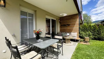 Gemütliche Terrasse mit Essbereich und Lounge-Ecke, umgeben von einem gepflegten Garten und Bergblick.