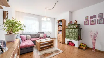 Gemütliches Wohnzimmer mit Kachelofen, Laminatboden und bequemer Eckcouch für entspannte Stunden.