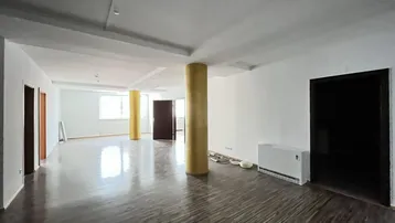 Geräumiger, leerer Wohnbereich mit dunklem Holzboden und gelben Säulen, ideal zur individuellen Gestaltung.