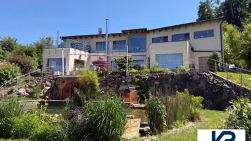 Großzügiges Anwesen mit weitläufigem Garten, Teichanlage und moderner Architektur in grüner Umgebung.