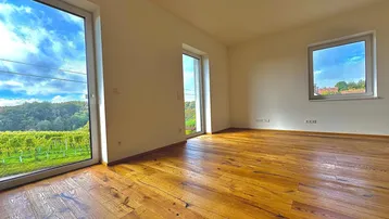 Helles Zimmer mit Holzboden und großen Fenstern, die einen weiten Blick auf die Weinberge bieten.