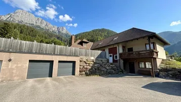 Geräumige Auffahrt mit Doppelgarage und Blick auf die umliegende Berglandschaft.