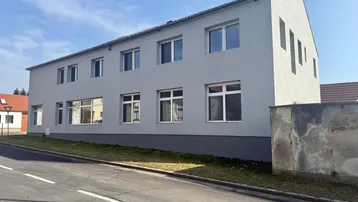 Modernes Gebäude mit heller Fassade und vielen Fenstern an einer Straße gelegen.