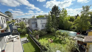 Weitläufiger Blick von oben auf die umliegenden Gebäude und den grünen Gartenbereich mit Gewächshaus.