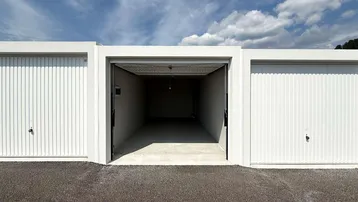 Außenansicht mehrerer Garagenboxen, eine davon mit geöffnetem Tor und Blick ins Innere.