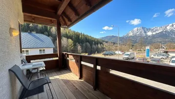 Sonniger Balkon mit Sitzgelegenheiten und weitem Blick auf die Berge und Umgebung.