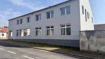 Modernes Gebäude mit grauer Fassade und vielen Fenstern an einer Straße gelegen.