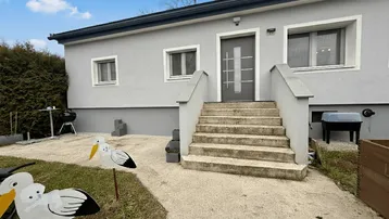 Vorderansicht des Hauses mit modernem Eingangsbereich, Treppe und gepflegtem Vorgarten.
