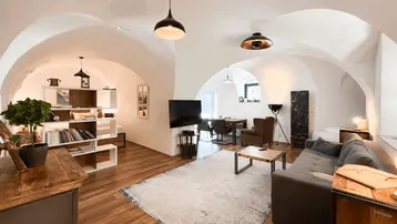Geräumiger Wohn- und Essbereich mit Gewölbedecken, Holzboden und moderner Einrichtung.