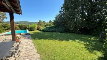 Terrasse und weitläufiger Garten mit Rasenfläche und Fernblick auf die Hügellandschaft.