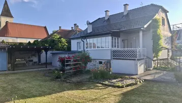 Gepflegter Garten mit Rasenfläche, Terrasse und Blick auf die umliegende Bebauung und Kirche.