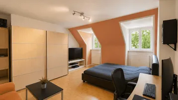 Helles Schlafzimmer mit Dachschrägen, integriertem Arbeitsbereich und großem Kleiderschrank.