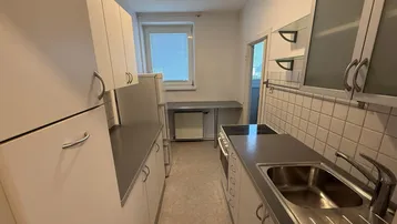 Funktionale Küche mit weißen Schränken, Fliesenrückwand und integriertem Kochfeld.