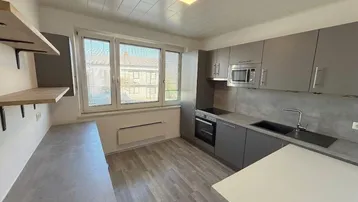 Moderne Küche mit grauen Schränken, integrierten Geräten und einem Fenster mit Blick nach draußen.