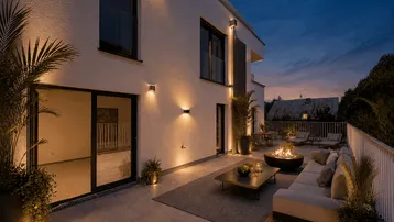Moderne, möblierte Terrasse mit Feuerstelle und Pflanzen, ideal für entspannte Abende im Freien.