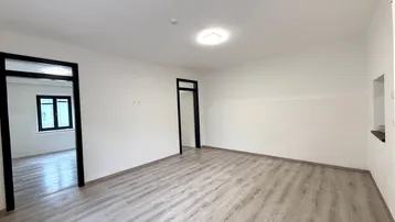 Helles, unmöbliertes Zimmer mit Laminatboden und Zugang zu weiteren Räumen in einem Neubau.