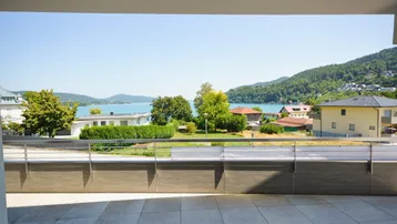 Panoramablick von der Terrasse auf den glitzernden See und die malerische Berglandschaft in der Ferne.