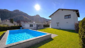 Sonniger Gartenbereich mit Pool und Blick auf die umliegende Berglandschaft.