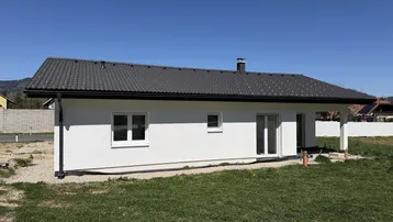 Modernes Einfamilienhaus mit weißer Fassade und dunklem Ziegeldach in ländlicher Umgebung.