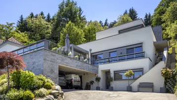 Moderne Architektur mit weißer Fassade, integrierter Garage und einer Terrasse im Obergeschoss.