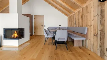 Gemütlicher Essbereich mit Kamin, Holzwänden und einer integrierten Sitzbank für gesellige Runden.