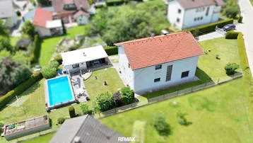 Luftaufnahme eines Einfamilienhauses mit Garten, Pool und umliegender Wohngegend.