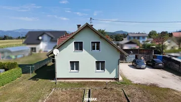 Ansicht des Einfamilienhauses mit hellgrüner Fassade, rotem Dach und Gartenbereich im Vordergrund.
