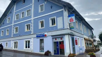 Blau gestrichenes Gebäude mit mehreren Fenstern und einem Sparkassen-Eingang im Erdgeschoss.