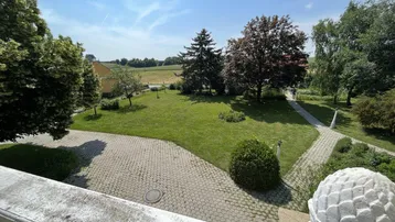 Panoramablick von der Terrasse über den gepflegten Garten und die umliegende grüne Landschaft.