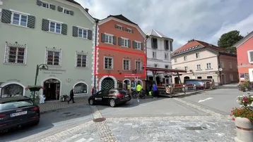 Historisches Gebäude in einer belebten Straße mit traditioneller Architektur und Geschäften im Erdgeschoss.