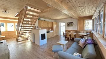 Offener Wohn-Essbereich mit Holzbalkendecke, Kamin und integrierter Küche im Landhausstil.
