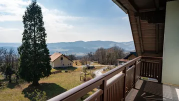 Balkon mit weitem Blick über die grüne Landschaft und die umliegenden Berge.