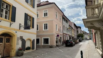 Historische Gasse mit Kopfsteinpflaster und charmanten Altbauten unter bewölktem Himmel.