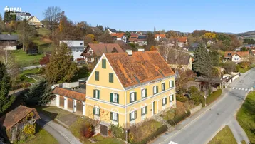 Luftaufnahme eines historischen gelben Gebäudes mit Ziegeldach in ländlicher Umgebung.