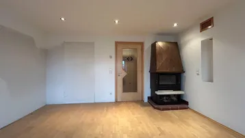 Geräumiges Wohnzimmer mit Holzboden und einem traditionellen Kamin als zentralem Element.