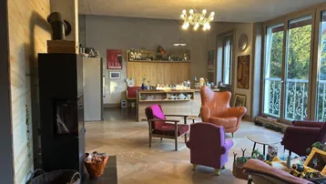 Gemütlicher Wohnbereich mit Kamin, Parkettboden und Blick auf die offene Bar.
