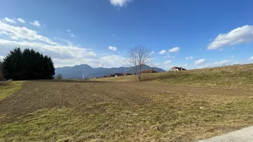 Weites Grundstück mit Blick auf die umliegende Landschaft und Berge unter blauem Himmel.
