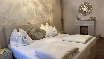 Geräumiges Schlafzimmer mit großem Bett, eleganter Tapete und einem dekorativen Kamin.