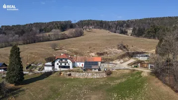 Luftaufnahme des Anwesens mit Photovoltaikanlage auf dem Dach und weitläufiger Hügellandschaft.