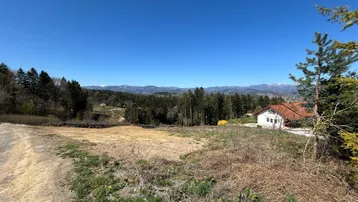 Weitläufiges Grundstück mit vorbereiteter Baufläche und Fernblick auf die umliegende Landschaft und Berge.