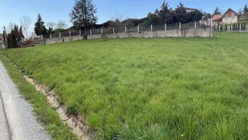Großes grünes Grundstück mit Wiese, umzäuntem Bereich und Häusern im Hintergrund.