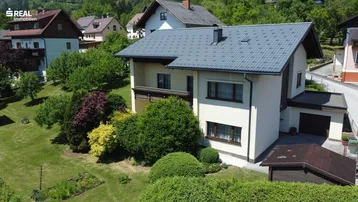 Ansicht des Hauses von oben mit gepflegtem Garten, Bäumen und umliegender Wohnbebauung.