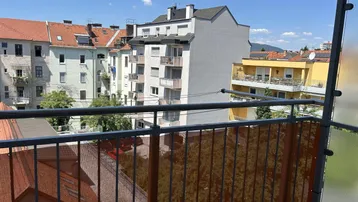 Blick vom Balkon auf die umliegenden Gebäude und Dächer der Stadt an einem sonnigen Tag.