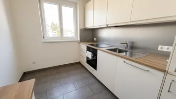 Moderne Küche mit weißen Schränken, Holzarbeitsplatte und Fenster, ideal für den täglichen Gebrauch.